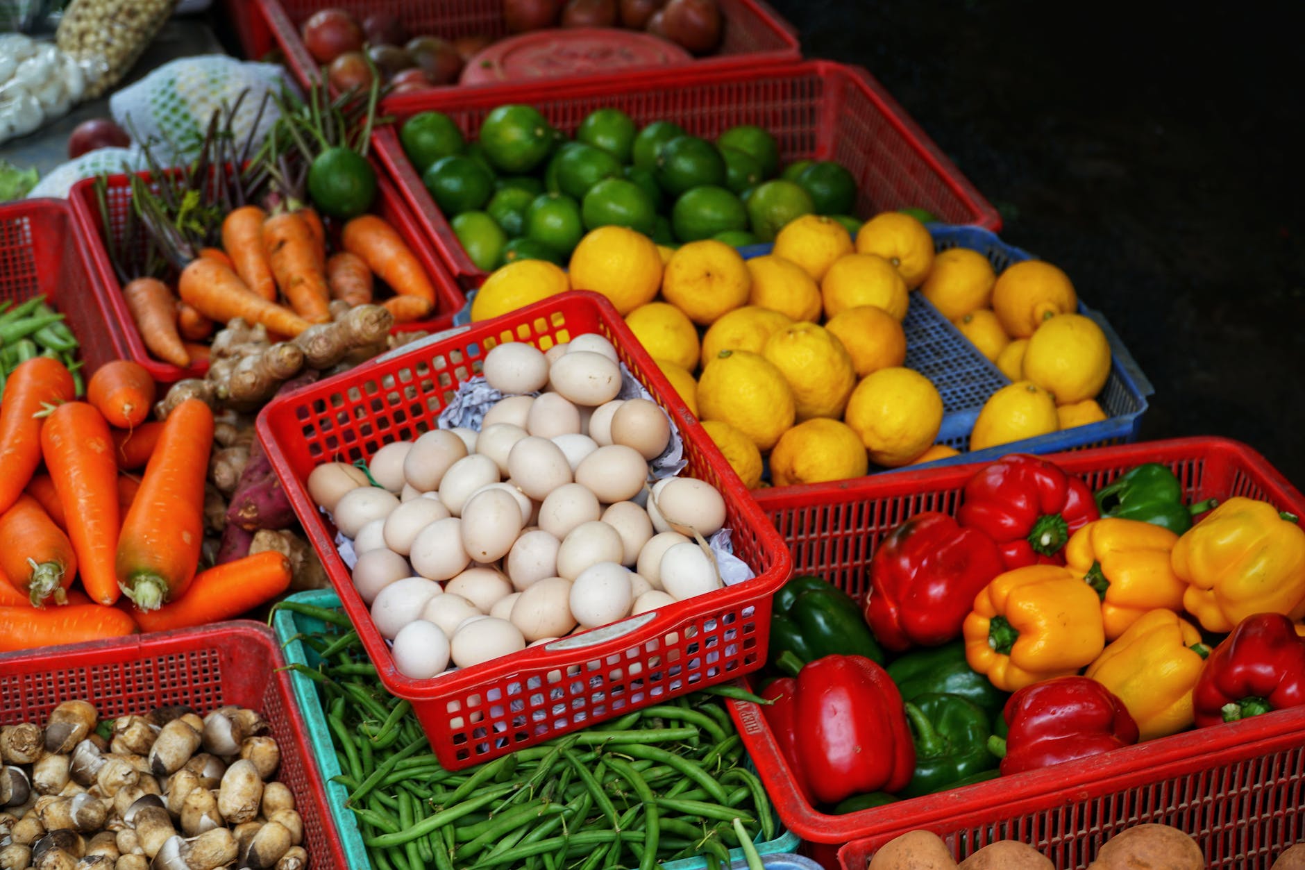 assorted fresh vegetables and eggs in containers in market